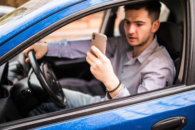 Motorista olhando para o celular com o carro parado